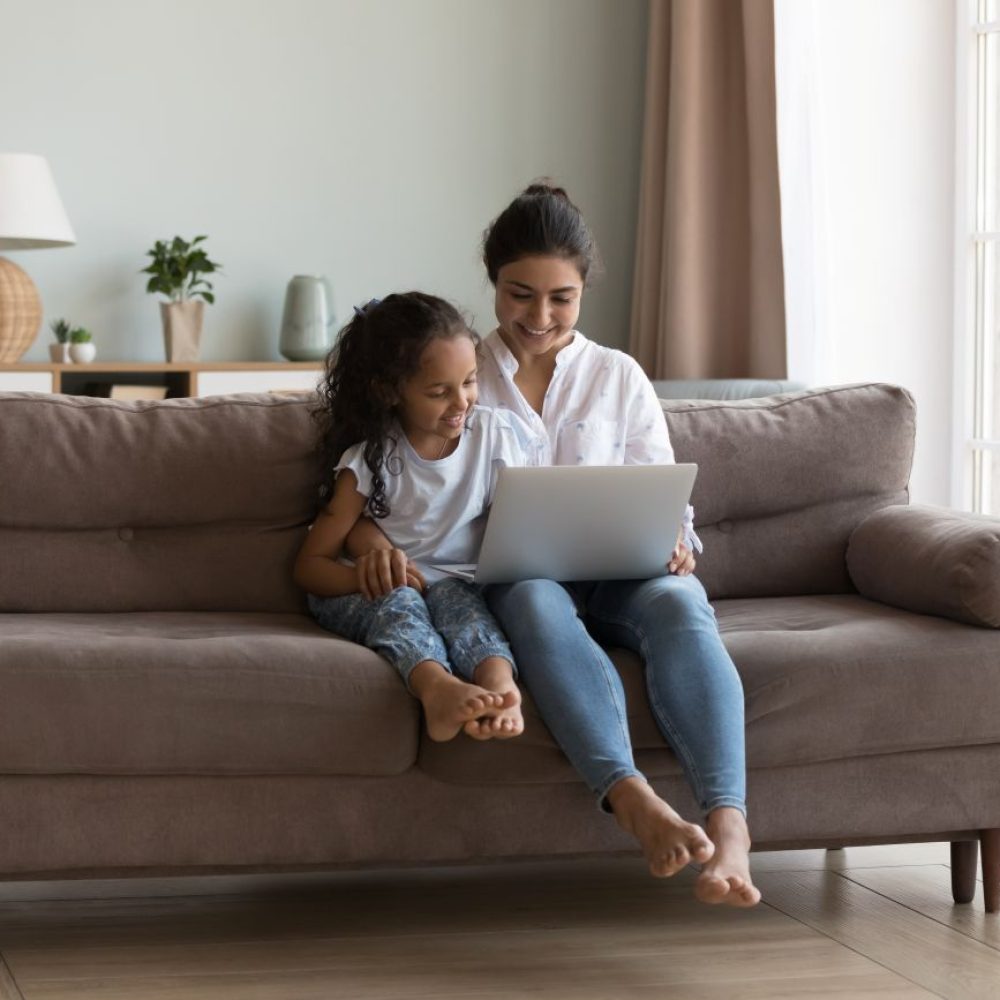 A woman and her daughter using a laptop at home